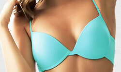 Close-up picture of a woman wearing a turquoise blue bathing suit top, showing the results of a breast reconstruction procedure.