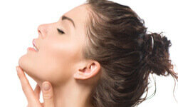 Portrait picture of a woman holding one hand to her chin showing a chin implant procedure.