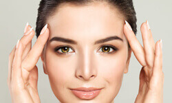 Close-up picture of a woman looking into the camera, showing the results of an eyebrow lift.