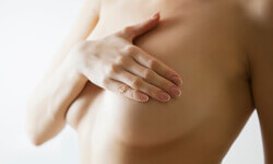 Picture of a woman holding her hand to her breast showing the benefits of a Mastopexy procedure.