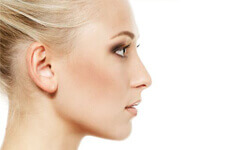 Side view photo of a woman who is pleased with her nose surgery procedure.