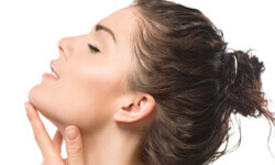 Side view picture of a woman holding her hand to her chin showing the results of a submental liposuction procedure.