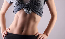 Frontal view of a woman’s abdomen showing a tummy tuck with abdomen and waist liposuction procedure she had.