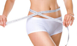 Picture of a woman holding a tape measure around her, showing the results of a vibroliposuction procedure.