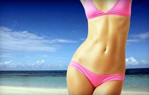 Picture of a slender woman standing on the beach with the ocean behind her, depicting her happiness with the pubic liposuction procedure she had in Costa Rica.
