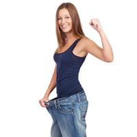 Picture of a woman standing in oversize jeans, showing the obesity treatment she had in Costa Rica.