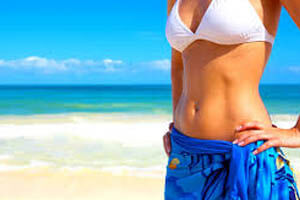 Picture of a woman standing on a beach, proud of her abdomen and hips liposuction in Costa Rica