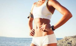 Picture of a woman with two hands on her hips, showing her Abdominoplasty procedure she had in Costa Rica.