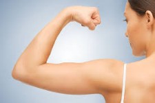 Photo of a woman holding up her left arm to show the results of her Brachioplasty procedure in Costa Rica.