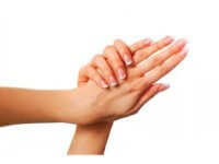 Close-up picture of a woman holding her hands to the camera showing the benefits of a hand surgery (fat transfer to the hands) she had in Costa Rica.