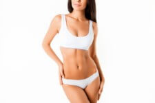 Picture of a woman wearing a white two piece outfit showing her post weight-loss body contouring that she had she had in Costa Rica.