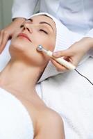 Picture of a woman lying on a table, with a doctor performing a laser mole removal procedure.