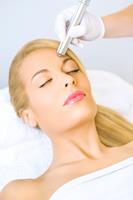 Portrait picture of a woman lying on a table, with a doctor performing a seborrhea Keratosis treatment