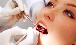 Picture of a smiling woman in a dental chair as a dentist is extracting a tooth.