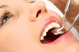 Picture of a smiling woman in a dental chair as a dentist is extracting a tooth.