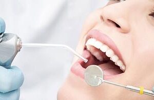 Picture of a smiling woman in a dental chair as a dentist is performing a dental fillings procedure.