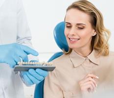 Picture of a smiling woman sitting in a dental chair, illustrating the availability of holistic ceramic dental implants procedure in Costa Rica.