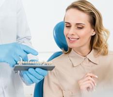 Picture of a smiling woman sitting in a dental chair, illustrating the availability of holistic ceramic dental implants procedure in Costa Rica.