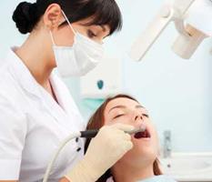 Picture of a woman sitting in a dental chair with a dentist standing beside her, performing a holistic oxygen treatment in Costa Rica.