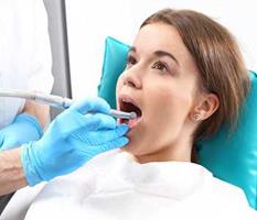 Picture of a smiling female in a dental chair showing her happiness with the holistic pediatric dental treatment she is receiving.