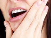 Picture of a woman holding a hand under her chin, showing her happiness with the holistic temporo-mandibular treatment she had in Costa Rica.