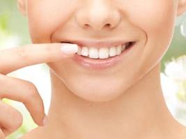 Picture of a smiling woman pointing to the invisible braces on her teeth, showing her happiness with the Invisalign procedure she had in Costa Rica.