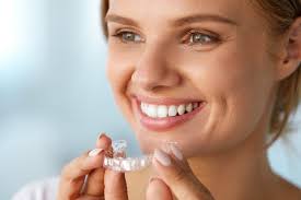 Picture of a smiling woman holding invisible braces, showing her happiness with the Invisalign invisible braces procedure she had in Costa Rica.