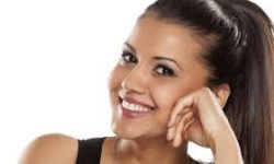 Picture of a smiling woman with her head slightly tilted and with her hand on her cheek, showing her happiness with the jaw surgery procedure she had in Costa Rica.