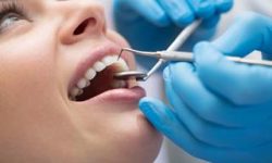 Picture of a smiling woman in a dental chair as a dentist is performing an oral pathology procedure.