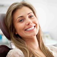 Picture of a smiling woman in a dental chair showing her happiness with the oral pathology procedure she is having in Costa Rica.