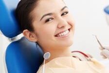 Picture of a smiling woman in a dental chair as a dentist is performing an orthognathic procedure.