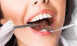 Picture of a smiling woman in a dental chair as a dentist is performing a periodontal surgery procedure.