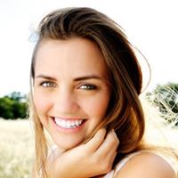 Picture of a smiling woman with her hand under her chin, happy with her TMJ disorder pain treatment she received in Costa Rica.