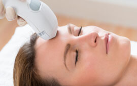 Picture of a woman lying down, and having a Fractional CO2 laser treatment.